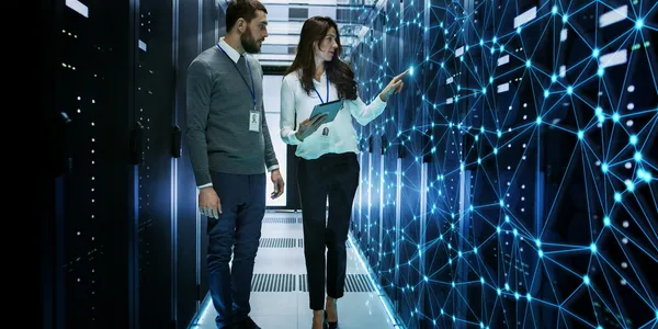 A man and a woman working in a server room